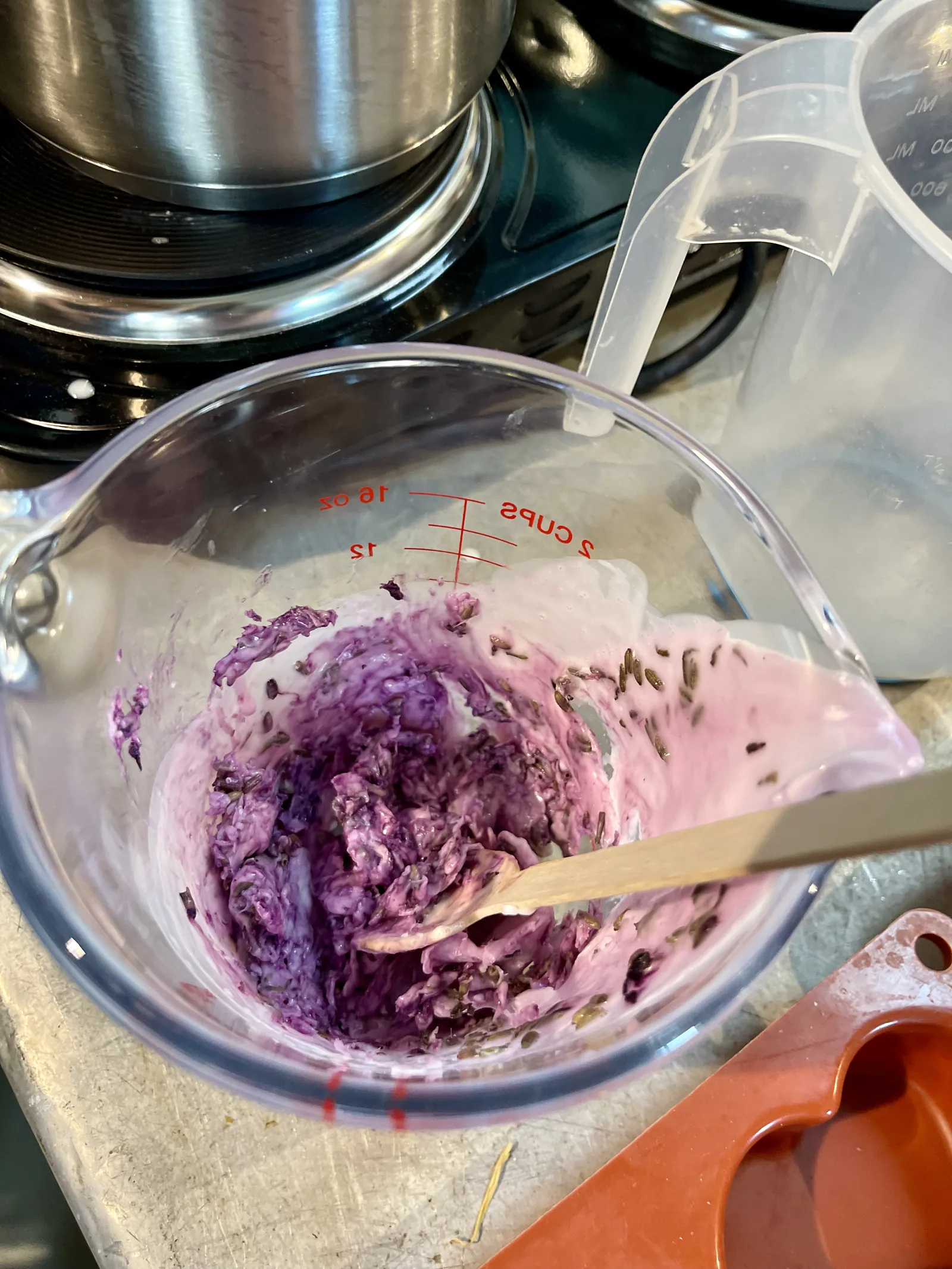 Una caraffa graduata con la base colorata di viola e la lavanda, mescolata con un bastoncino