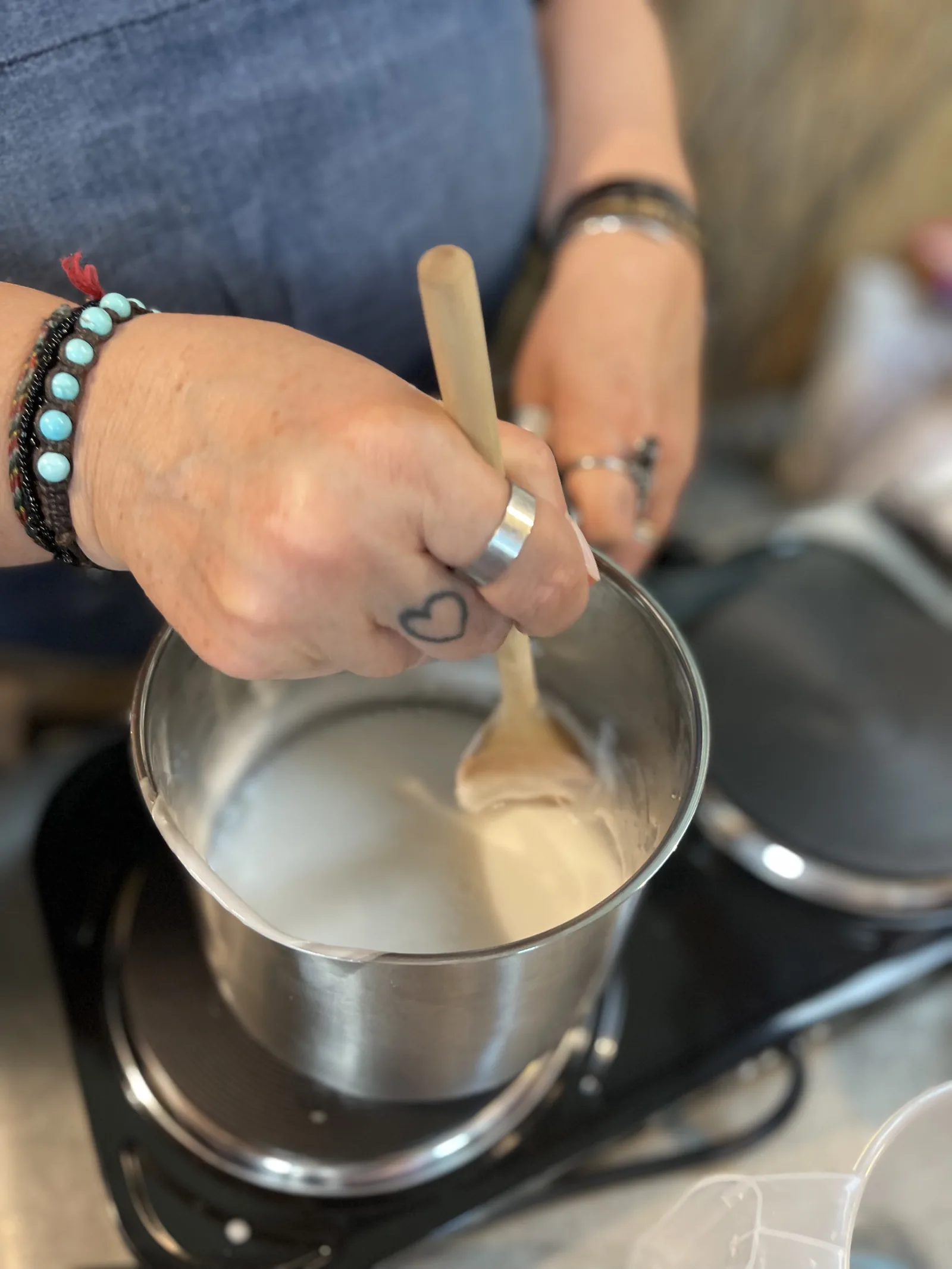 Mani che mescolano la base bianca sciolta in un pentolino, sulla piastra