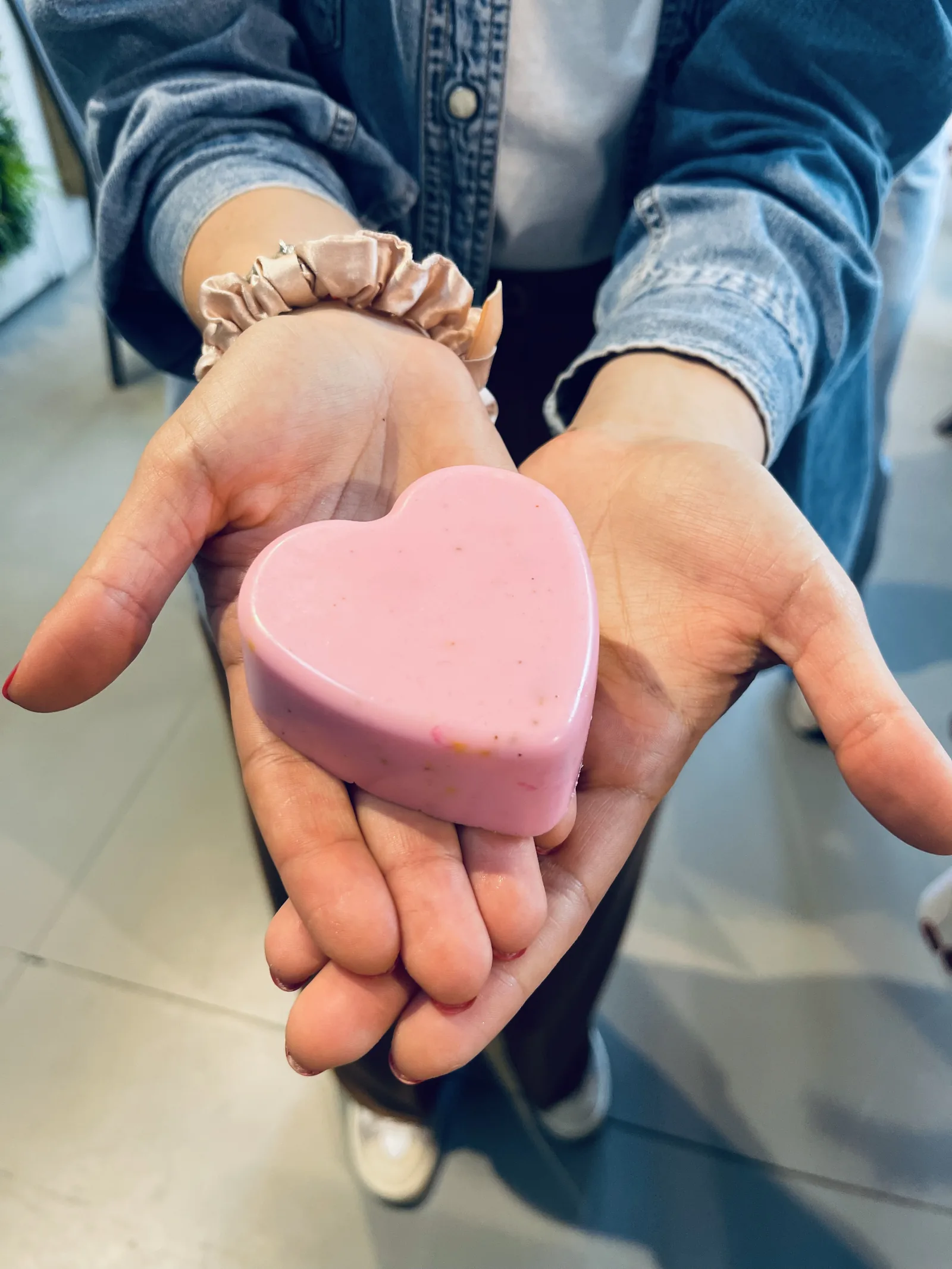 Due mani tengono un sapone rosa a forma di cuore