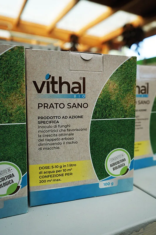 Una scatola di prodotto biologico per il prato, color cartone con la foto di un prato verde, sullo scaffale del negozio