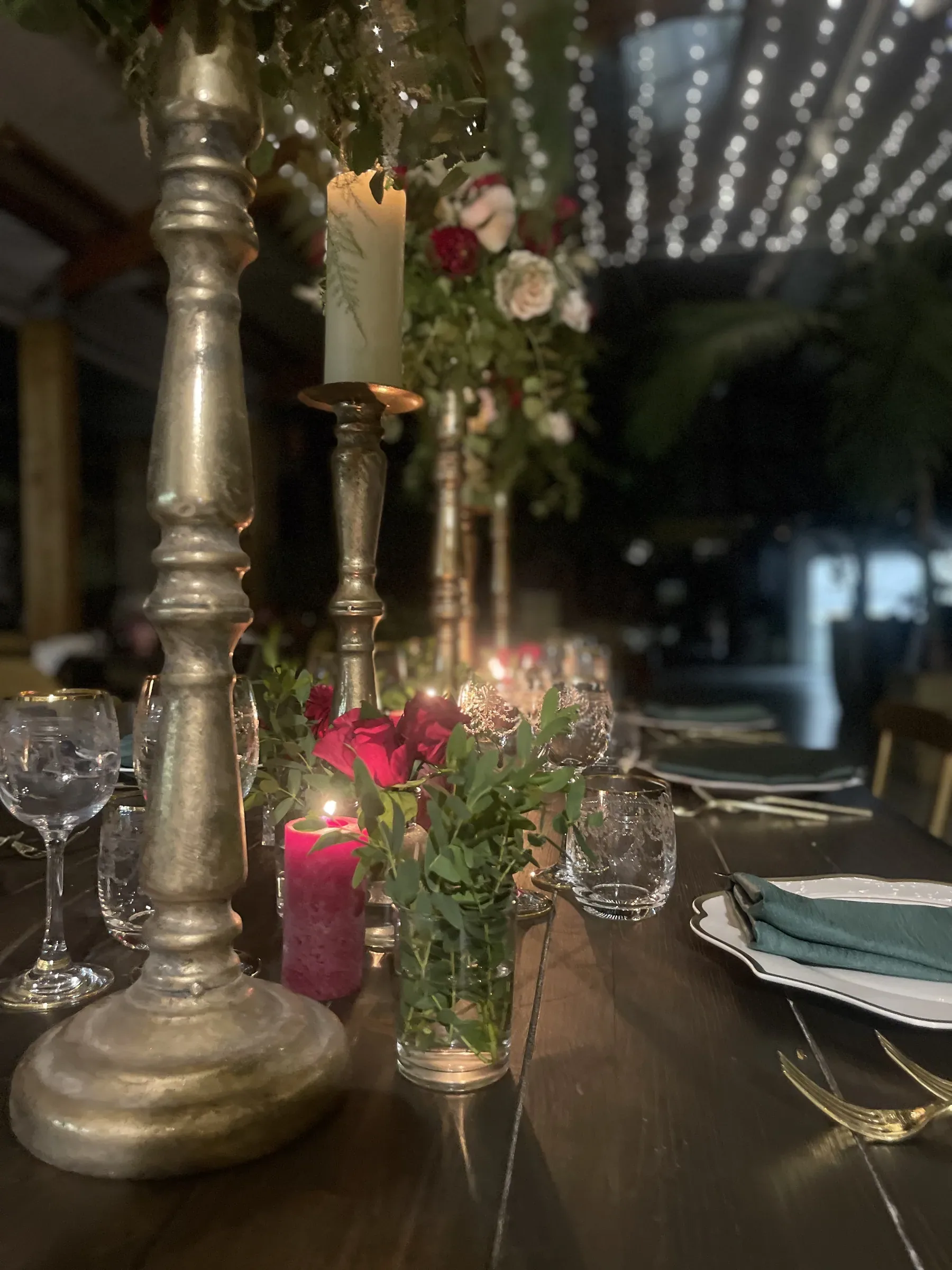 Candeliere dorato in primo piano con le rose rosse e le lucine sullo sfondo