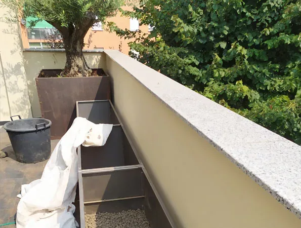 Prima: il terrazzo durante i lavori, con le fioriere lunghe ancora vuote, un telo bianco e l'ulivo già piantato nella fioriera alta sul fondo