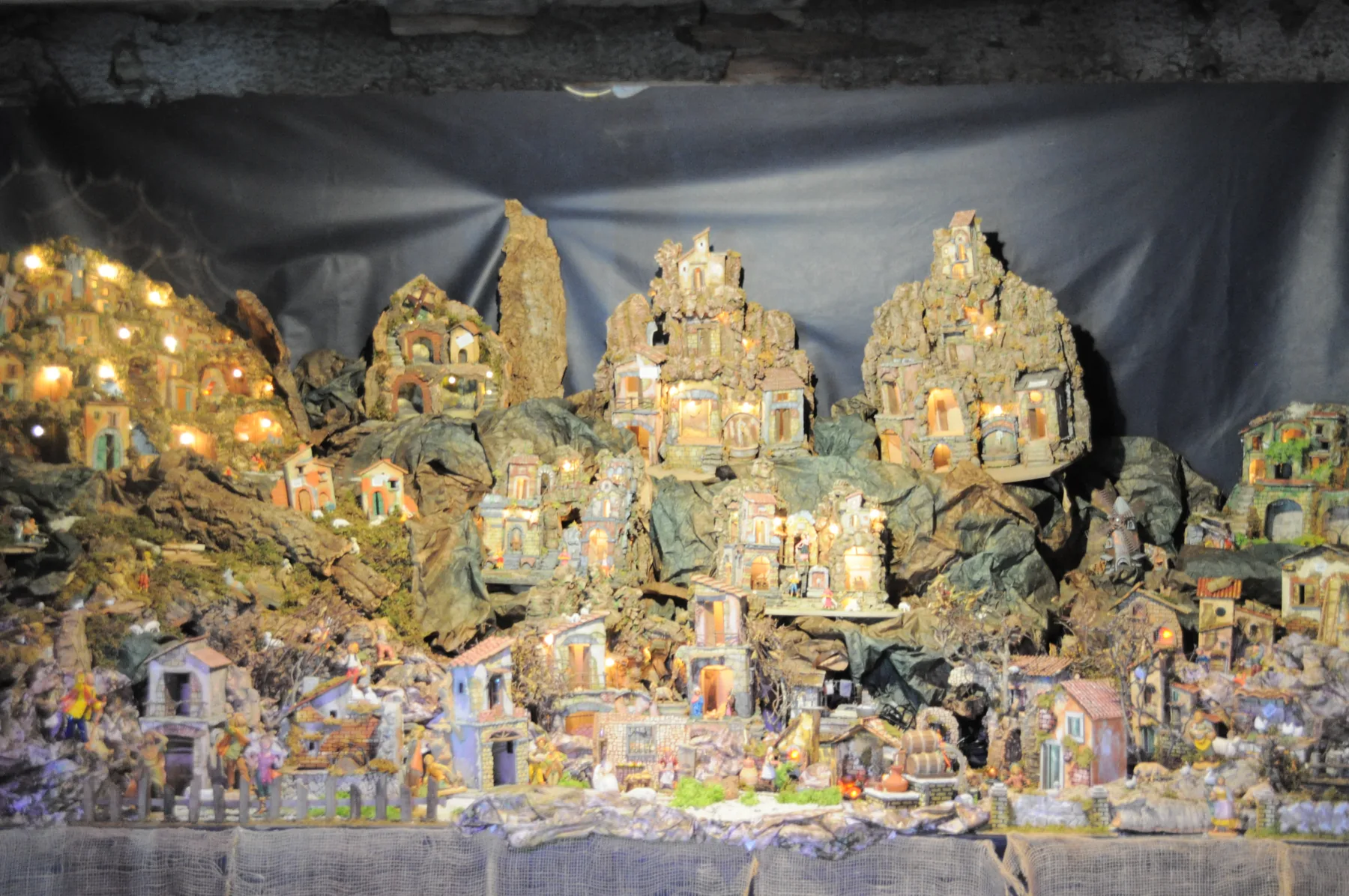 Grande presepe con borghi di casette illuminate arroccate sulle rocce, grotte e statuine