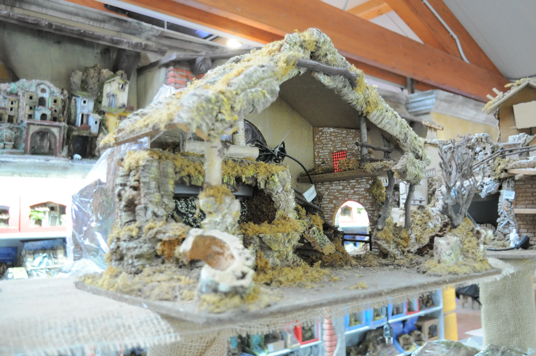 Capanna del presepe con il tetto di corteccia e muschio, esposta su un banco