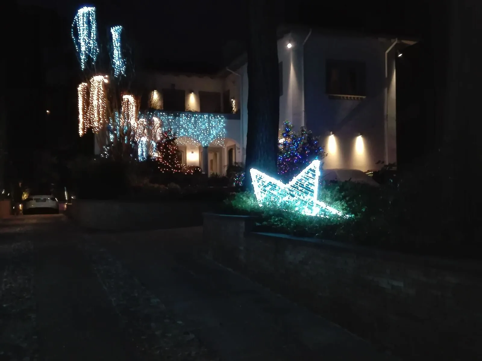 Villa di notte con cascate di luci sugli alberi del giardino e una grande stella luminosa fra gli arbusti