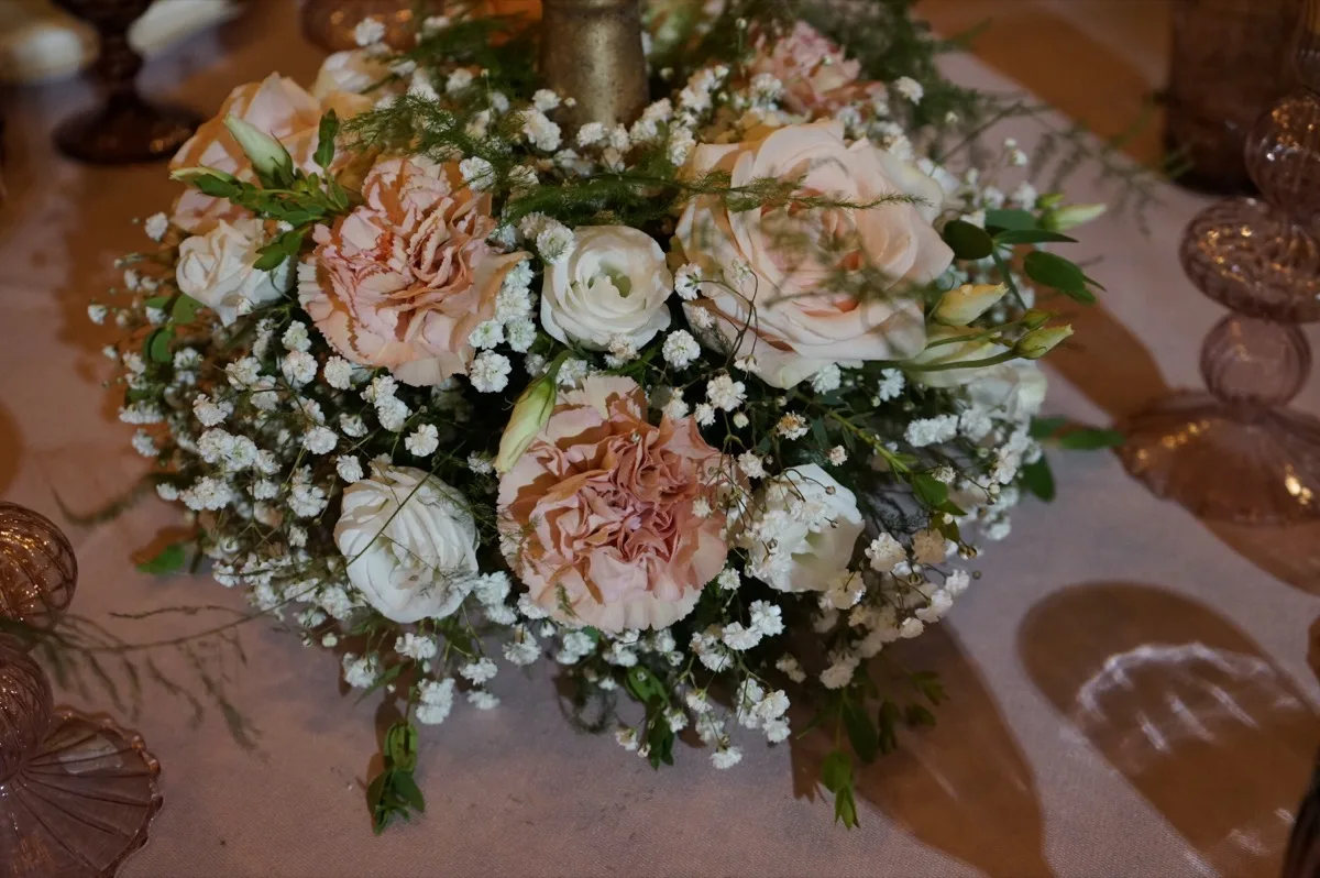 Centrotavola rotondo di garofani rosa, rose e lisianthus bianchi con la gypsophila, visto dall'alto